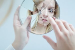 Five Ways We Deceive Ourselves (but not others) - woman looking into broken mirror